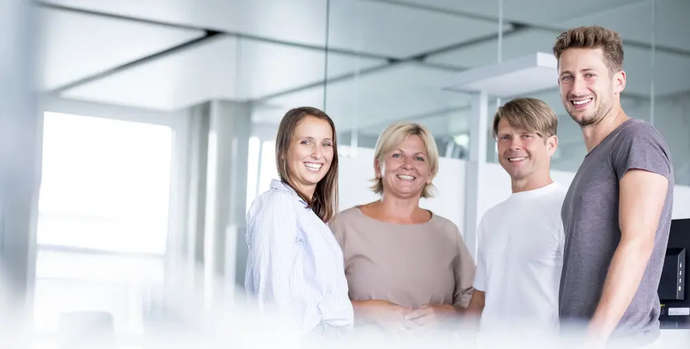 © www.Lindner-Group.com / Sonstige/Kommerziell 4 lachende Menschen in einem modernen Büro